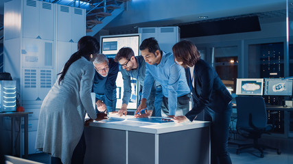 Fototapete - Engineers Meeting in Technology Research Laboratory: Engineers Scientists and Developers Gathered Around Illuminated Conference Table, Talking and Finding Solution, Inspecting Industrial Engine Design