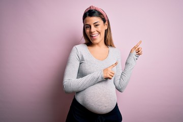 Sticker - Young beautiful brunette woman pregnant expecting baby over isolated pink background smiling and looking at the camera pointing with two hands and fingers to the side.