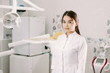 © etonastenka - cheerful female dentist smiling in her office. dentistry student standing in a dental treatment room