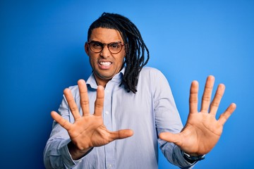 Wall Mural - Young handsome african american man with dreadlocks wearing casual shirt and glasses afraid and terrified with fear expression stop gesture with hands, shouting in shock. Panic concept.