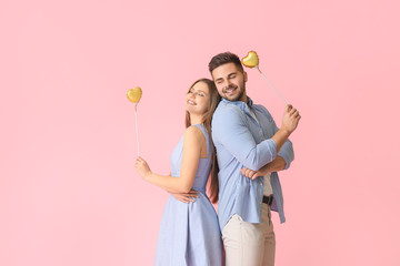 Wall Mural - Happy young couple with hearts on color background