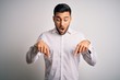 © Krakenimages.com - Young handsome man wearing elegant shirt standing over isolated white background Pointing down with fingers showing advertisement, surprised face and open mouth