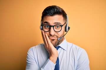 Poster - Young business operator man wearing customer service headset from call center thinking looking tired and bored with depression problems with crossed arms.