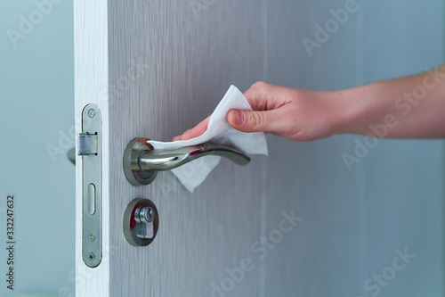 Photographie Person disinfects and cleans door handle with antibacterial wet wipes to protect against viruses, germs and bacteria during coronavirus outbreak and flu covid ncov epidemic