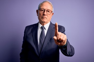 Grey haired senior business man wearing glasses and elegant suit and tie over purple background Pointing with finger up and angry expression, showing no gesture