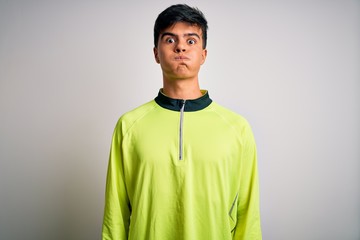 Wall Mural - Young handsome sportsman doing sport wearing sportswear over isolated white background puffing cheeks with funny face. Mouth inflated with air, crazy expression.