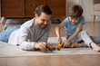 © fizkes - Happy young father lying on floor in living room with little son engaged in funny game together, smiling loving dad play with small preschooler boy child with animal toys, relax at home on weekend