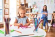 © Krakenimages.com - Caucasian girl kid playing and learning at playschool with female teacher. Mother and daughter at playroom around toys drawing with pencil colors