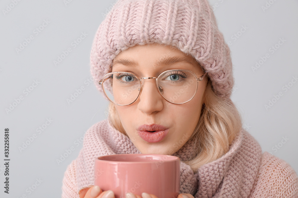 Beautiful young woman with cup of tea on grey background