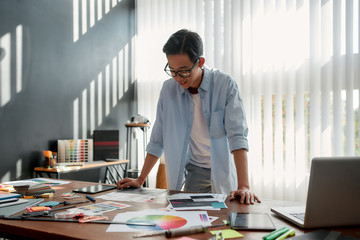 Wall Mural - satisfied with my work. happy asian man in eyeglasses analyzing new design project and smiling while