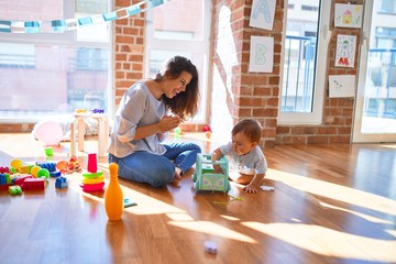 Poster - Beautiful teacher and toddler playing around lots of toys at kindergarten