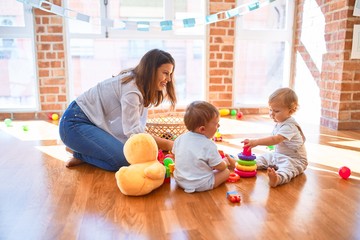 Poster - Beautiful teacher and toddlers playing around lots of toys at kindergarten