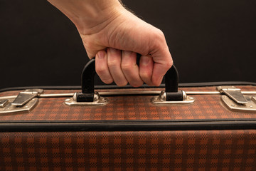 old suitcase with hand on black background