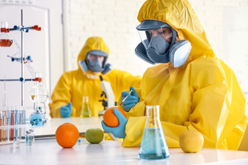 Poster - Scientist in chemical protective suit injecting orange at laboratory