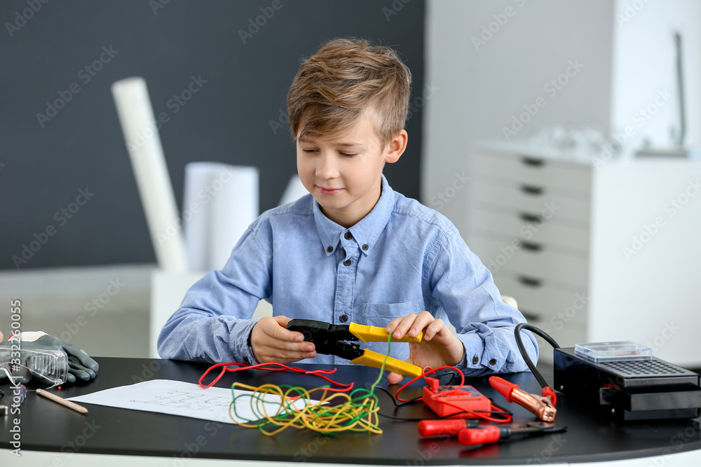 Cute little electrician performing wiring at table