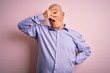 © Krakenimages.com - Middle age handsome hoary man wearing casual shirt standing over pink background peeking in shock covering face and eyes with hand, looking through fingers with embarrassed expression.