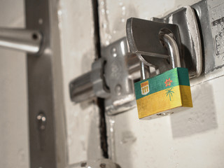 A bolted door secured by a padlock with the national flag of Saskatchewan on it.(series)