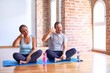 © Krakenimages.com - Middle age sporty couple sitting on mat doing stretching yoga exercise at gym smiling doing phone gesture with hand and fingers like talking on the telephone. Communicating concepts.