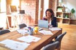 © Krakenimages.com - Middle age beautiful businesswoman smiling happy and confident. Sitting on chair working in a desk at the office