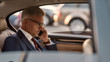 © Svitlana - Busy day. Confident and stylish mature businessman in full suit working on his laptop and talking on the phone with client while sitting in the car