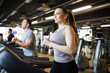 © Seventyfour - Waist up portrait of smiling young woman running on treadmill while enjoying cardio workout in modern gym, copy space
