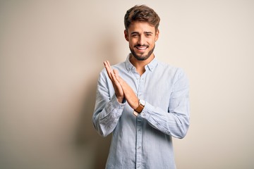 Wall Mural - Young handsome man with beard wearing striped shirt standing over white background clapping and applauding happy and joyful, smiling proud hands together