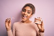 © Krakenimages.com - Young african american woman smiling happy holding professional orthodontic denture with metal braces and removable invisible aligner. Comparation of two dental straighten treatments