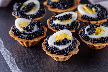 delicious snack tartlets on dark stone background