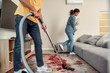 © Svitlana - Keep your family healthy. Happy multicultural couple in casual clothes cleaning their modern living room together. Young man cleaning the carpet with vacuum cleaner