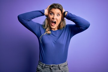 Sticker - Young beautiful blonde woman wearing casual t-shirt over isolated purple background Crazy and scared with hands on head, afraid and surprised of shock with open mouth