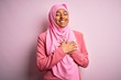 © Krakenimages.com - Young African American afro woman wearing muslim hijab over isolated pink background smiling with hands on chest with closed eyes and grateful gesture on face. Health concept.