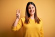 © Krakenimages.com - Young beautiful woman wearing casual sweater over yellow isolated background showing and pointing up with fingers number three while smiling confident and happy.