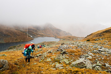 Tourists travelers with backpacks climb the rocks in dense fog. Poor visibility and easy to get lost. Caucasus Mountains, Arkhyz