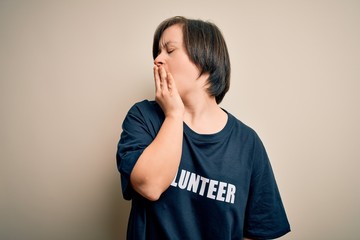 Canvas Print - Young down syndrome volunteer woman wearing social care charity t-shirt bored yawning tired covering mouth with hand. Restless and sleepiness.