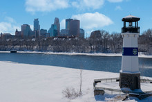 Winter In Minnesota. The Boom Island Lighthouse,Mississippi, River, With Downtown Minneapolis In The Background