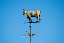 WEATHER VANE Made In A Shape Of A Cow, Attached To A Spire With Directional Points On A Roof Scallop
