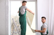 © New Africa - Professional workers tinting window with foil indoors
