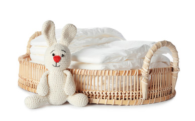Wall Mural - wicker tray with disposable diapers and toy bunny on white background
