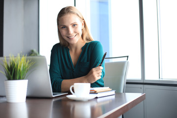 Beautiful smiling business woman is sitting in the office and looking at camera