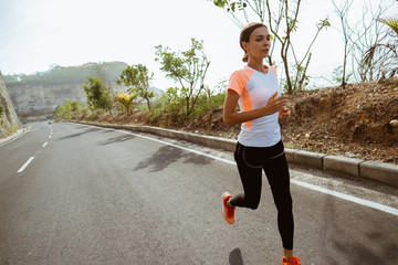 Wall Mural - sport woman running on sideroad. fit woman jogging on empty road