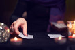 © Sergey Mironov - Close-up of fortuneteller's hands with fortune-telling cards at table with candles