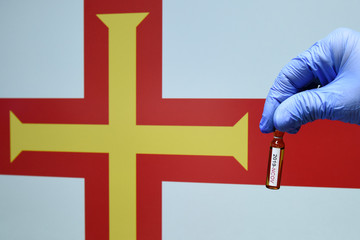 Corona virus or Covid-19 in Guernsey , sample blood tube in hand with Guernsey flag on background