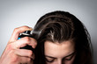 Woman applying dry spray shampoo on her dirty hair. Fast and easy way to keep your hair clean.