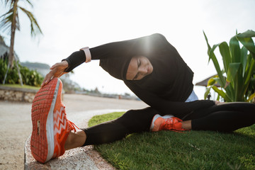 Wall Mural - woman with muslim sport wear stretching. sporty female using head scarf exercising