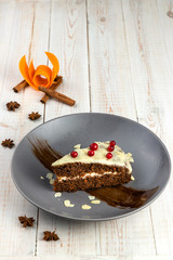 piece of carrot orange cake with mint and cranberries on white wooden background in rustic style, ex