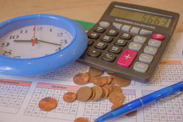 financial business calculation with calculator. coin stack with a clock background