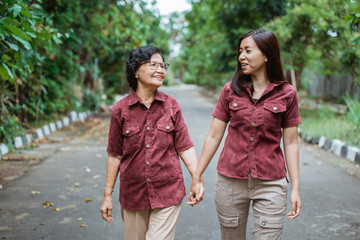 Asian grandmother enjoy chatting with her daughter's when walking in the park