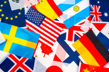 Many national flags are on the table. Bright background of national flags. Official state symbols. Banners from different countries of the world are photographed on the table.