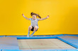 Happy little girl jumping on trampoline in fitness center