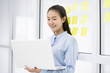 © sattahipbeach - Asian young businesswoman holding and using laptop computer at glass room office with sticky note backside
